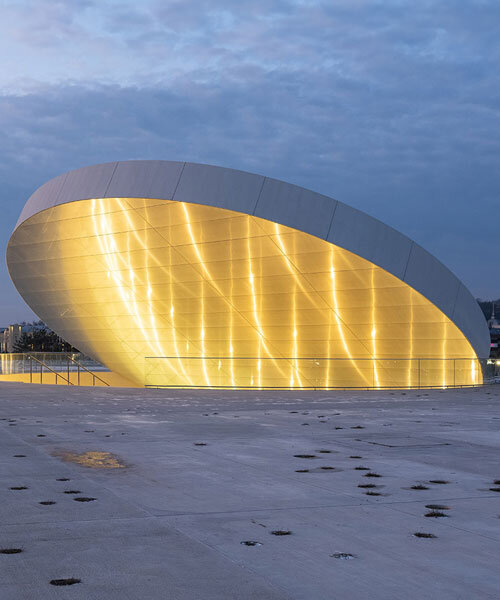 tilted reflective disk sits atop SMAR's science island museum in nemunas, lithuania